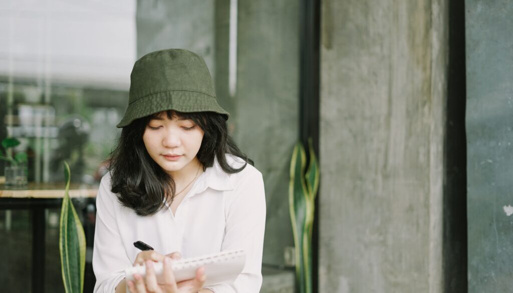 Lady wearing hat writing notes