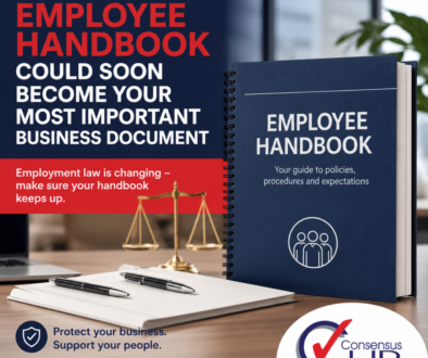 Promotional image of an Employee Handbook on a desk with a blue binder, scales of justice, pens, and the Consensus HR logo in the corner.