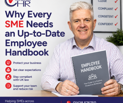 Smiling man in a striped shirt holds a gray 'Employee Handbook' booklet beside a poster that says 'Why Every SME Needs an Up-to-Date Employee Handbook' with a red checkmark logo.